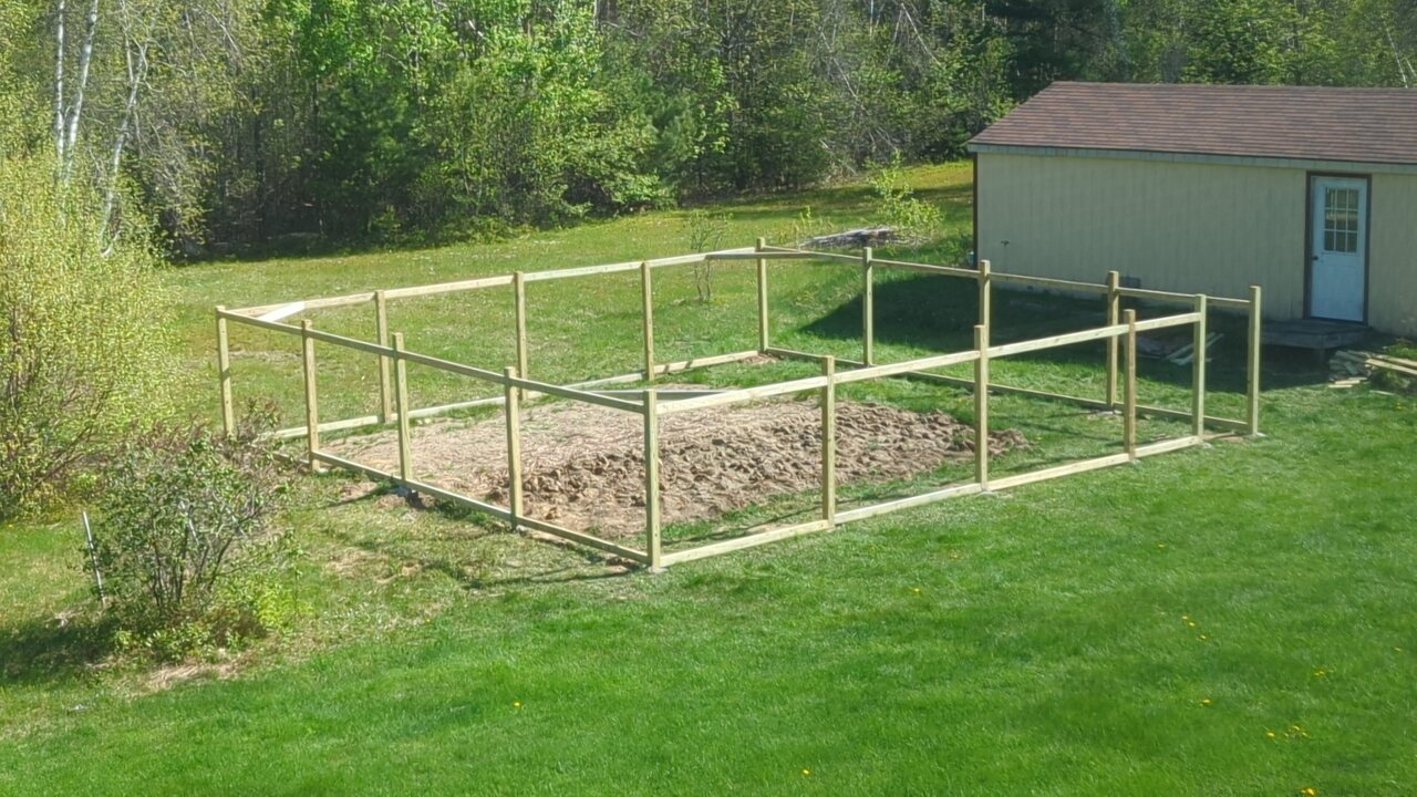 The partially completed fence with posts, rails, and corner braces installed